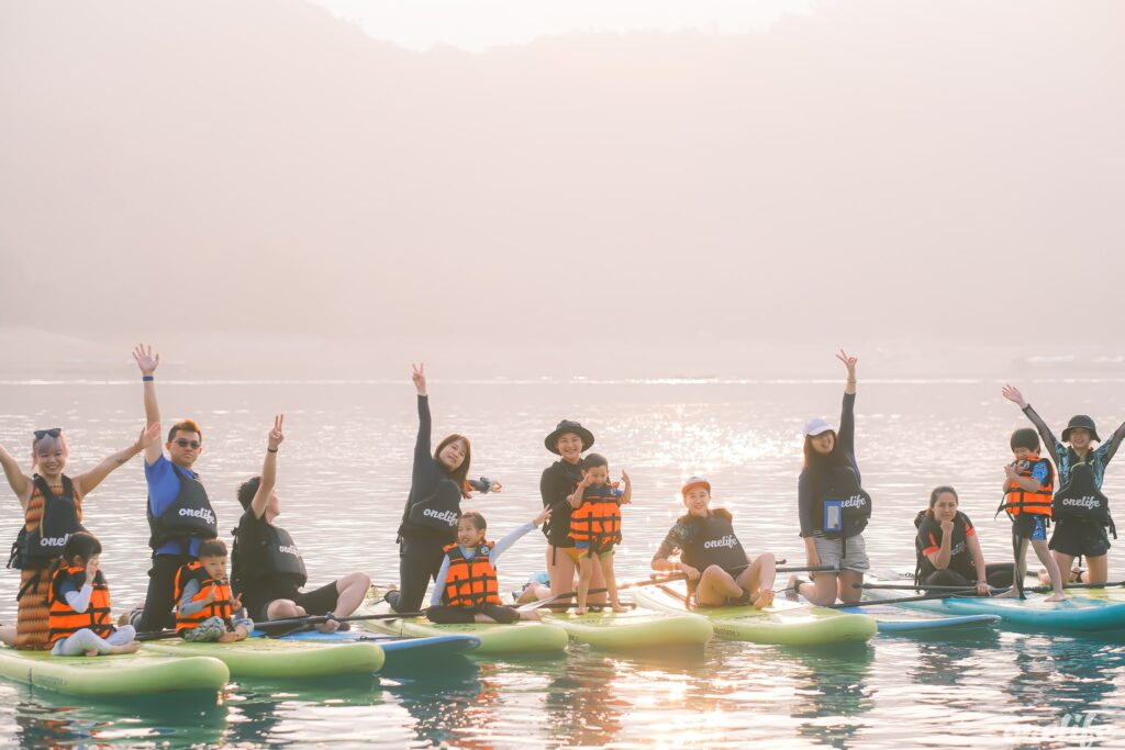 The OneLife SUP coaching team and family posing together at Sun Moon Lake